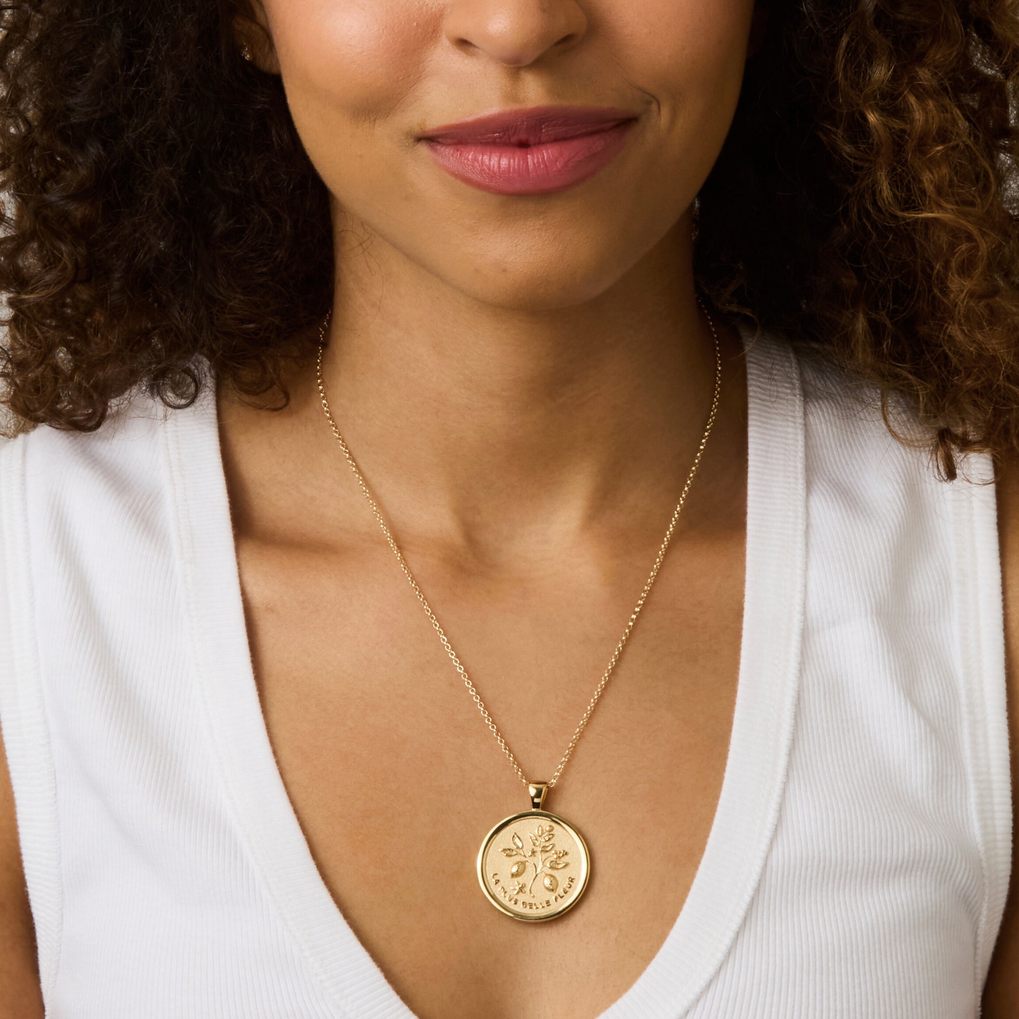 Model wearing gold gratitude coin pendant