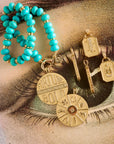 Stylized shot of lucky pendants and stone collector beaded necklace in turquoise on top of an illustration of an eye