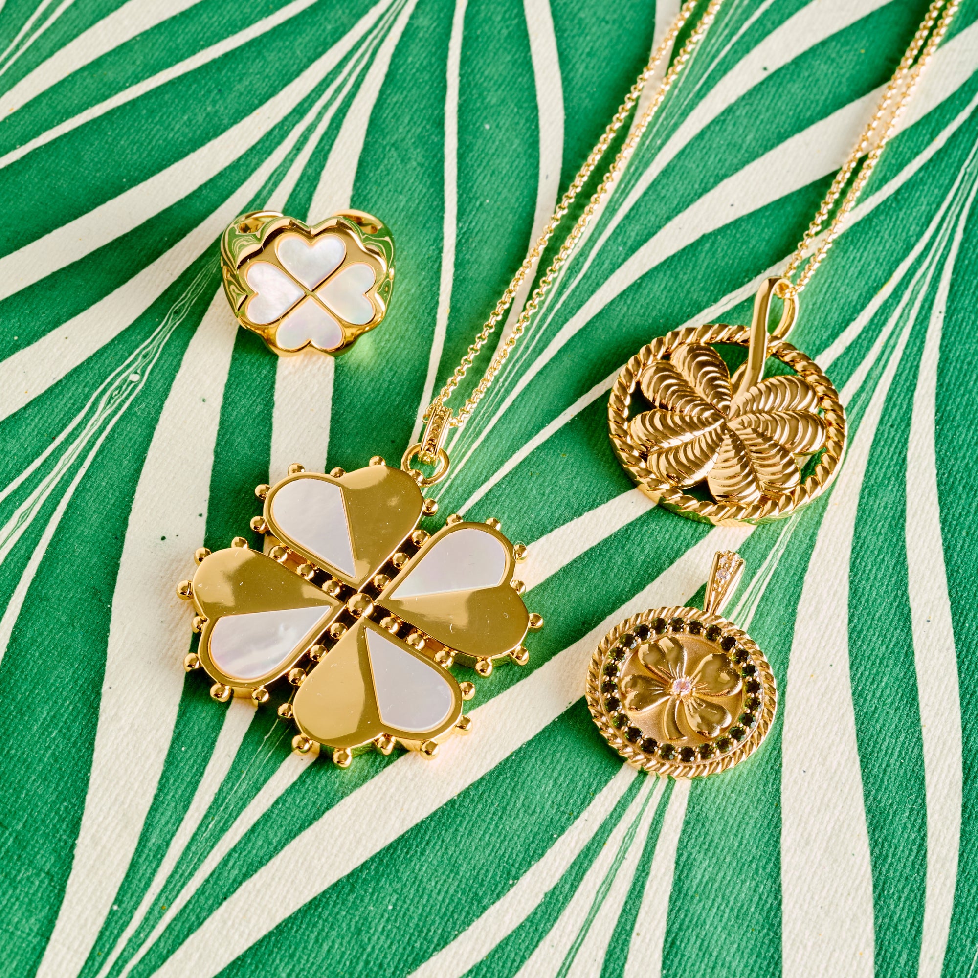 Stylized shot of lucky clover pendants and ring on green and white marbled paper