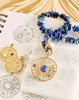Stylized shot of wanderlust coins and lapis beaded necklace on sketches of the designs