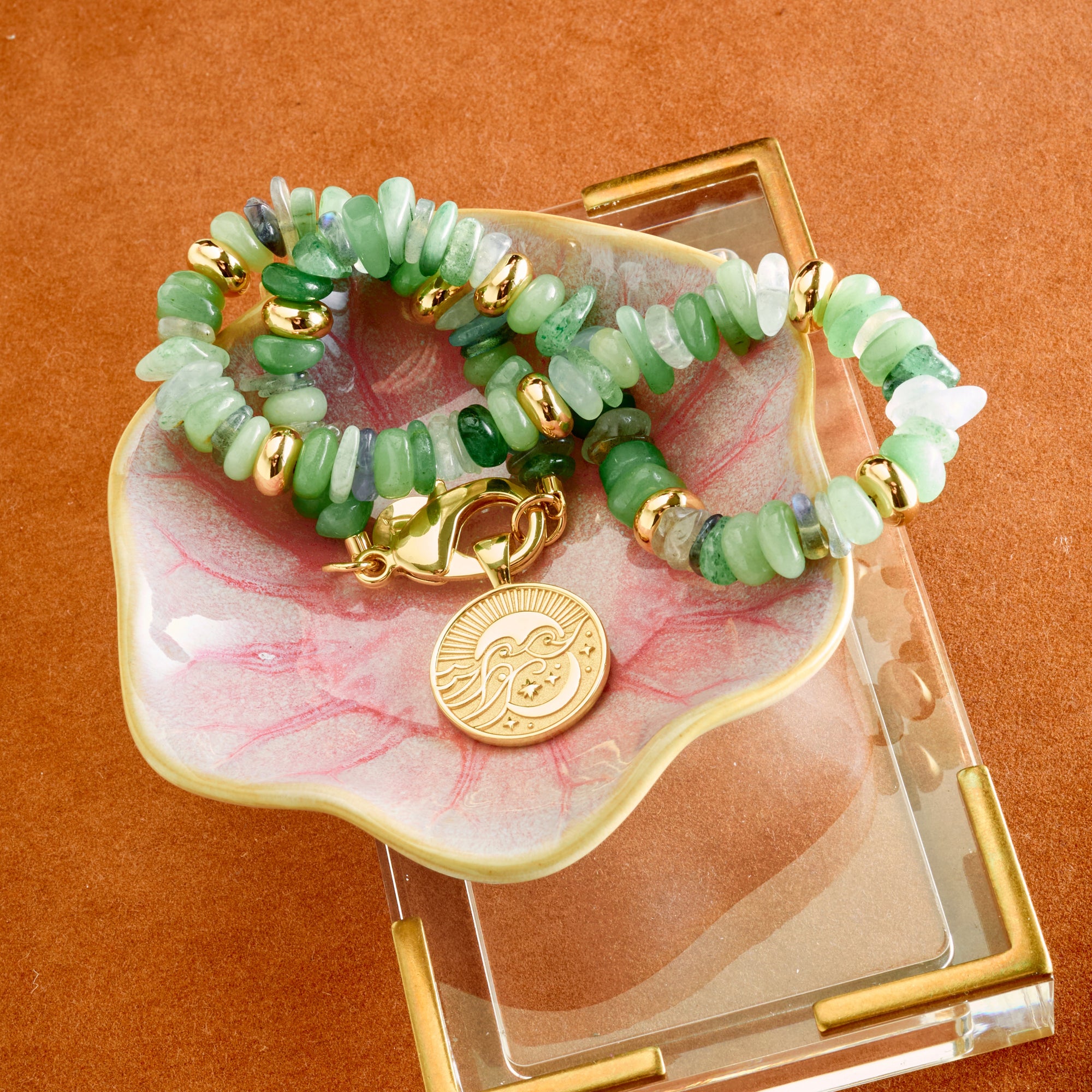Stylized shot of beaded seaglass necklace and small wanderlust coin in ceramic dish