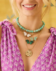 Model wearing the strong stone collector beaded necklace in amazonite, freedom stone butterfly necklaces and the gold original free coin
