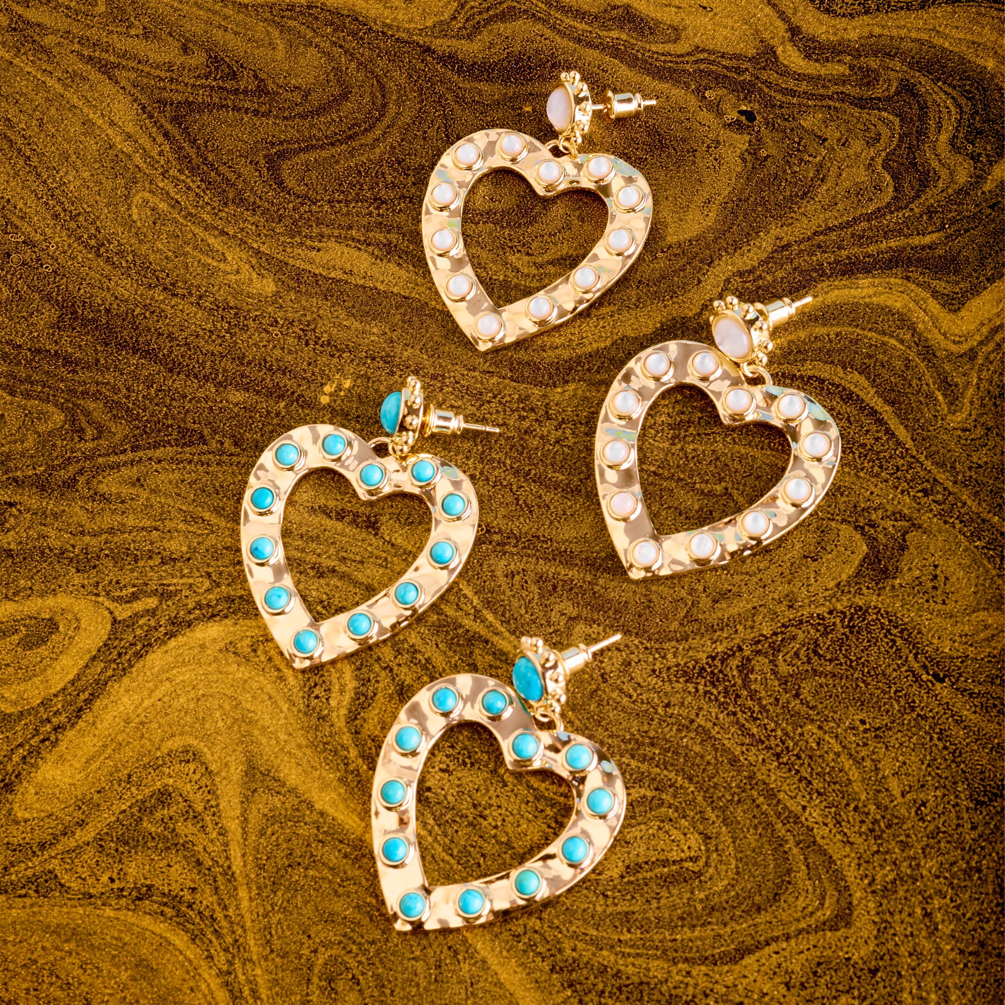 Stylized shot of the love in the sun earrings in turquoise and mother of pearl on marbled brown background