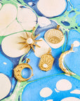 Stylized shot of moon, star, and sun pendants on blue and green marbled paper