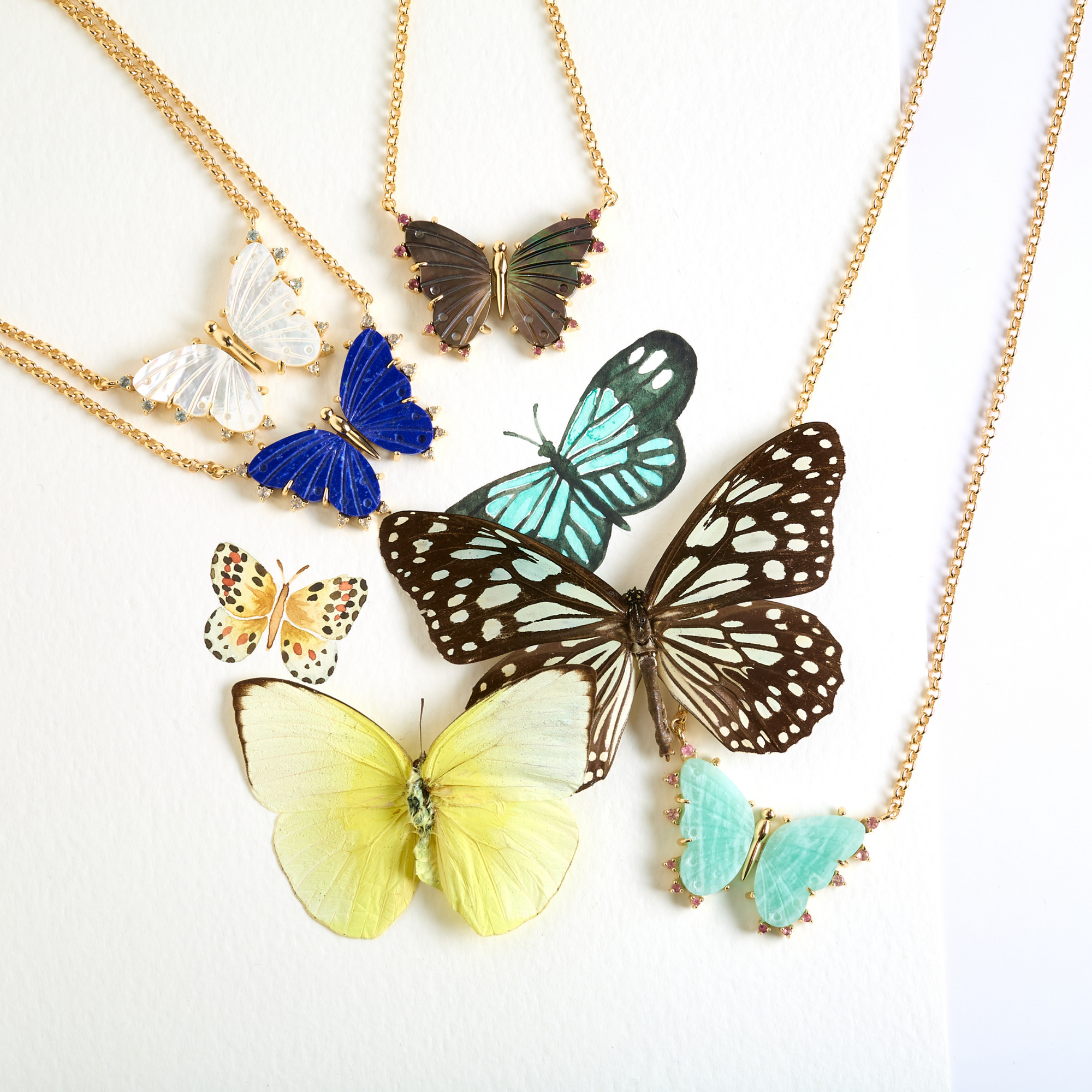 Stylized shot of various butterfly necklaces with watercolor and real butterflies