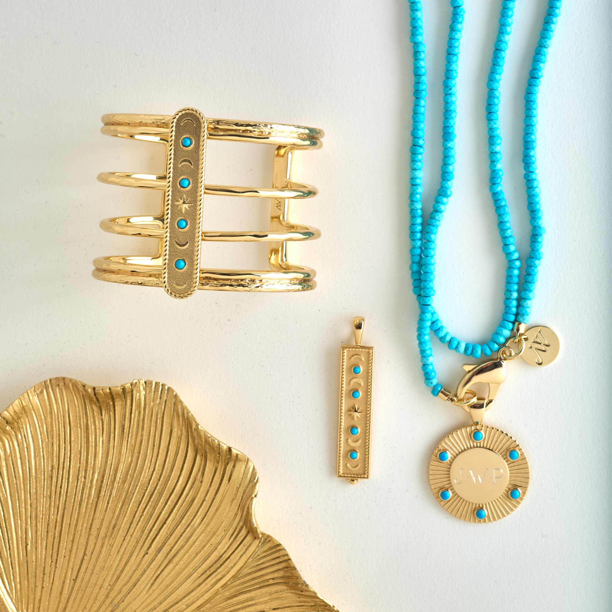 Stylized shot of gold and turquoise coin pendant, cuff, and dogtag