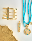 Stylized shot of gold and turquoise coin pendant, cuff, and dogtag