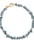 Beaded necklace features naturally shaped labradorite beads in shades of gray, small gold beads interspersed, and an oversized gold clasp