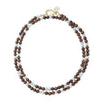 Double wrap beaded necklace features round wooden beads with pearl bead interspersed throughout. Necklace has oversized gold lobster clasp