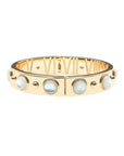 Gold hinge cuff bracelet features large mother of pearl cabochons on the outside, and then roman numerals with star details inside