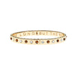 Thin gold hinge cuff features alternating cabochons of Mother of Pearl and tiger's eye stones on the outside and the phrase "the days are long but the years are short" inscribed on the inside.