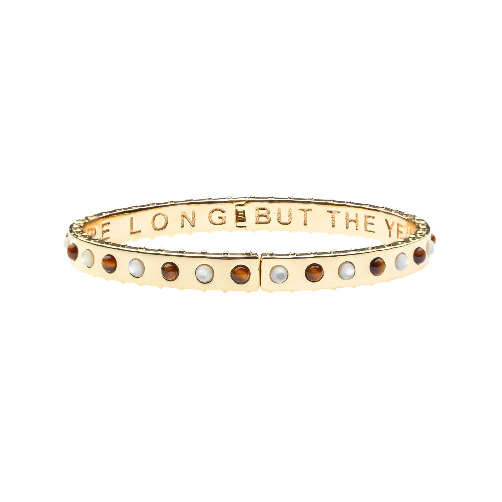 Thin gold hinge cuff features alternating cabochons of Mother of Pearl and tiger's eye stones on the outside and the phrase "the days are long but the years are short" inscribed on the inside.