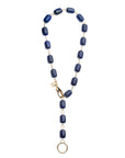 Necklace features chunky lapis beads with oversize gold lobster clasp and ring to attach pendants. Shown as a lariat.