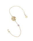 Gold chain bracelet featuring mini coin with illustration of the sun, waves, and a heart with pink tourmaline accent on chain