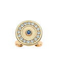 Gold ring features round evil eye motif with blue sapphire in the center and border of white topaz stones