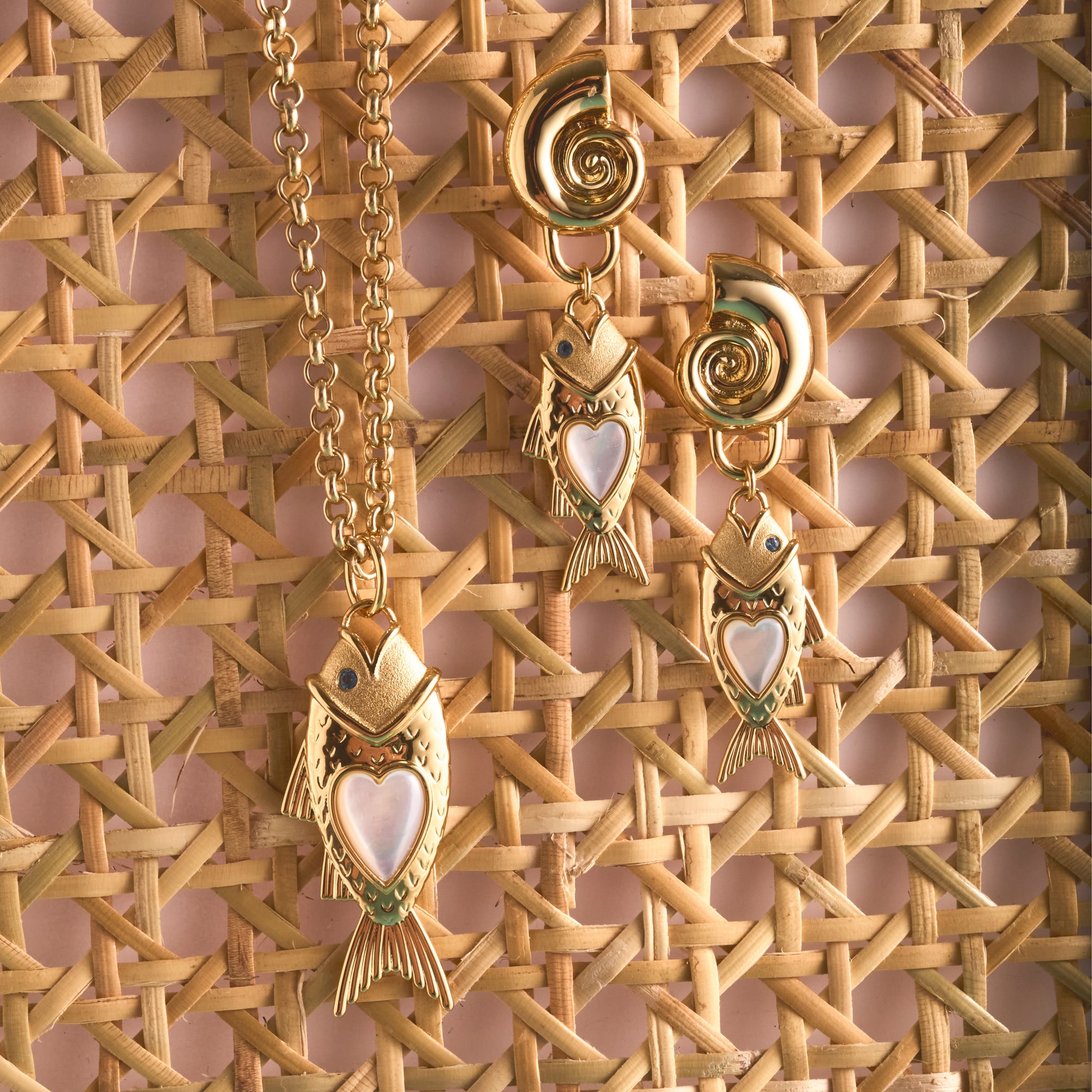 Stylized shot of strong amore fish pendant and strong amore fish earrings on rattan surface
