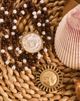 Stylized shot of strong enduring sun, strong ever shining sun, and wood and pearl double wrap in a basket with a seashell