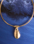 Stylized shot of the strong along the shore pendant on the neck cuff on a photo of a wave crashing