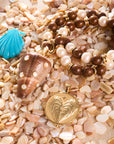 Stylized shot featuring the strong decked out shell pendant, carved turquoise shell, strong love of the sea coin, and the wood and pearl beaded necklace