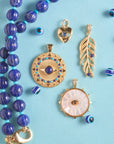 Stylized shot of lapis pumpkin beaded necklace, wanderlust palm leaf, protect gleaming eye, and protect eye of stone on turquoise background
