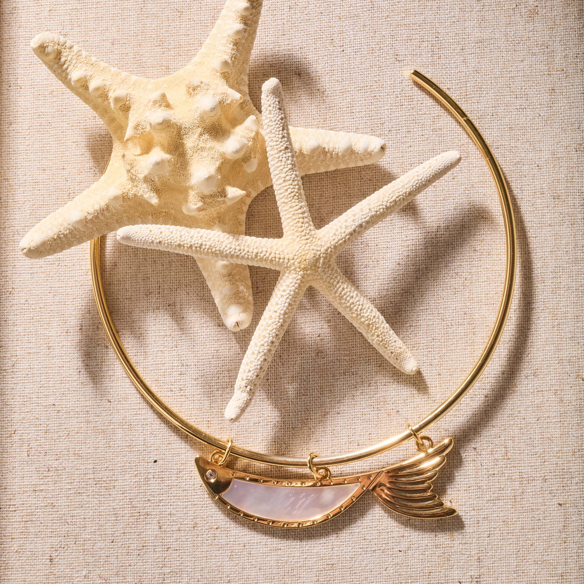 Stylized shot of the keep swimming fish on the gold neck cuff photographed with starfish