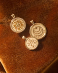 Stylized shot of the original gratitude coin, small gratitude coin, and the gratitude citrus slice embellished coin on an orange velvet background