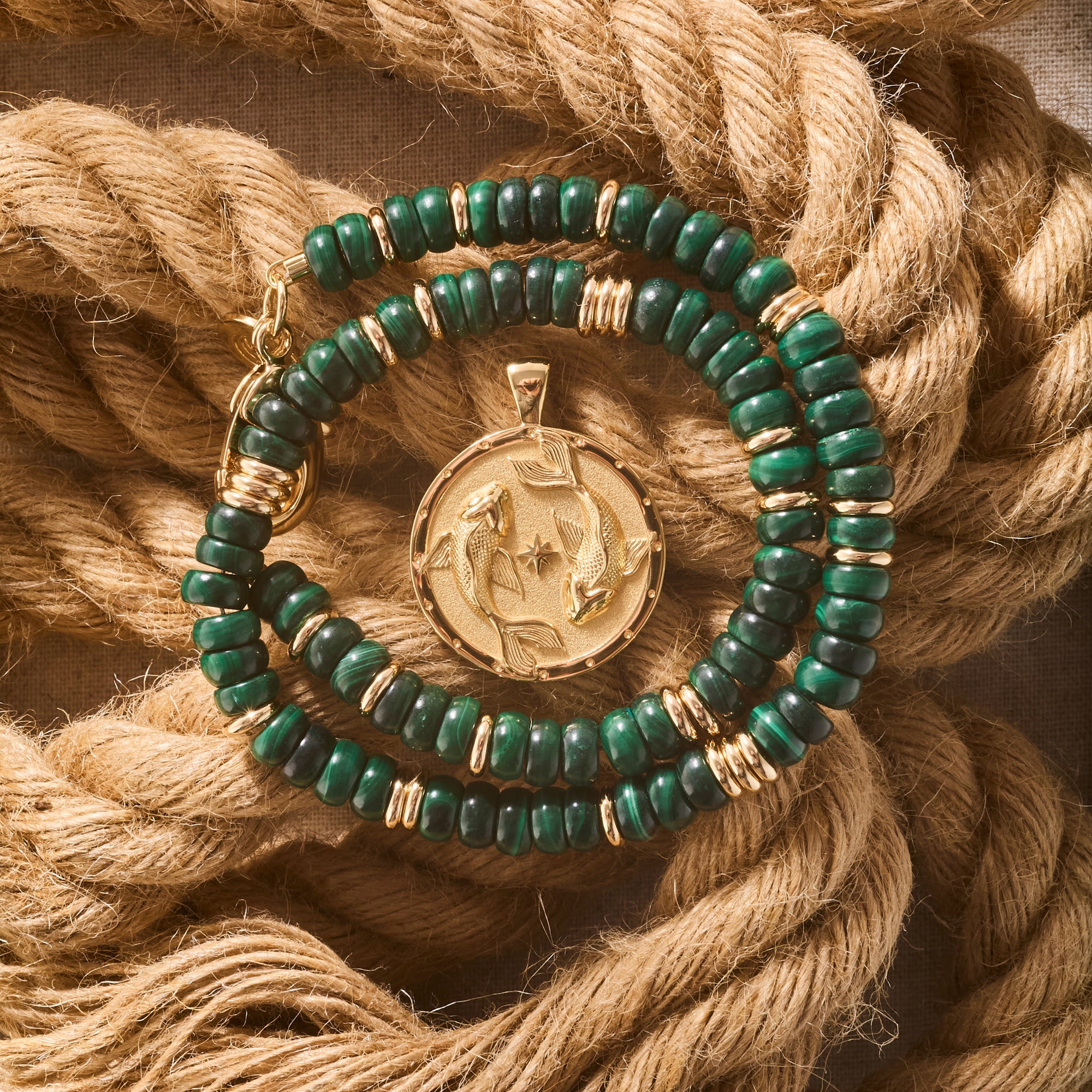 Stylized shot of the malachite gumdrop necklace and the strong circling koi coin pendant on a background of twisted ropes