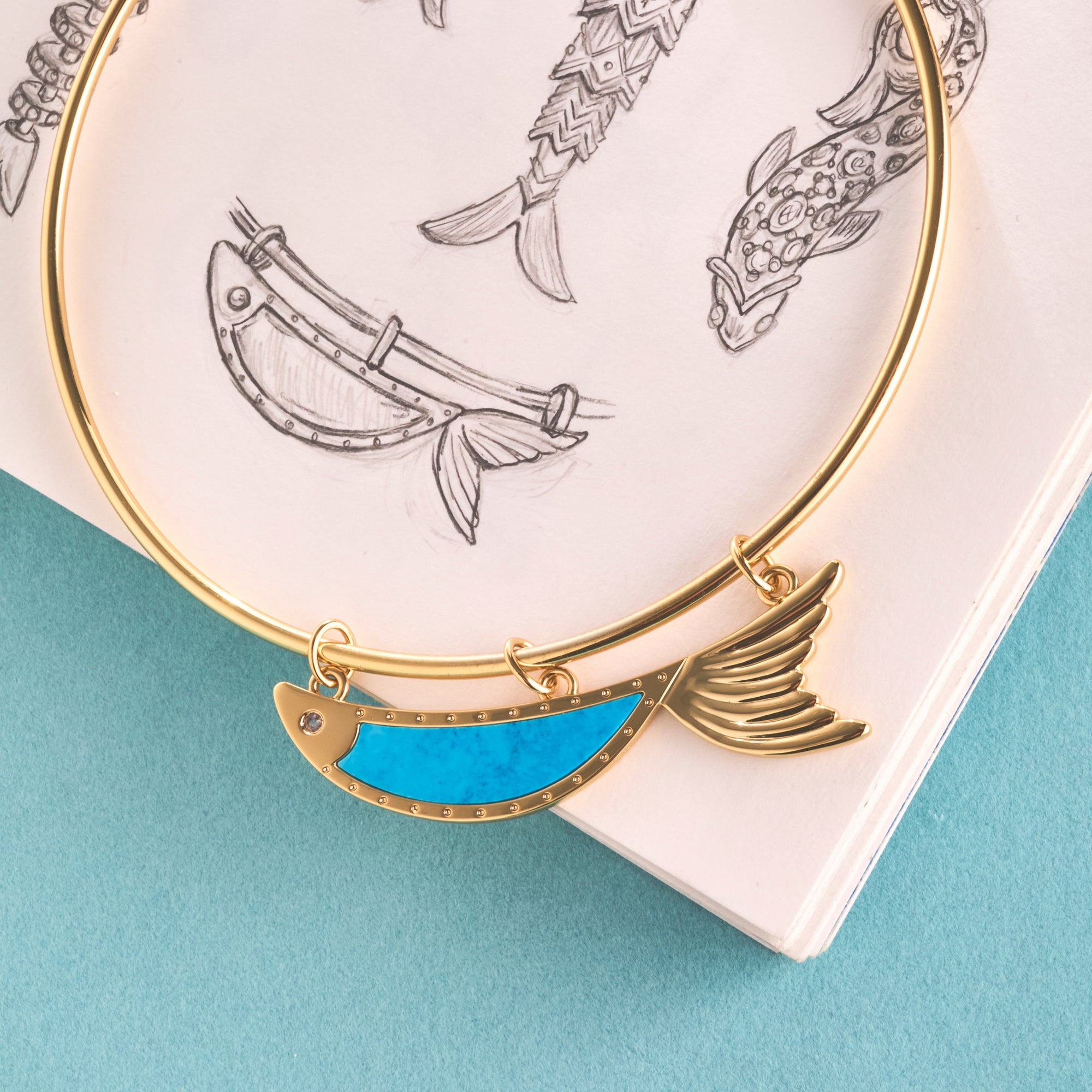 Stylized shot of the keep swimming fish in turquoise on top of a sketch of the design