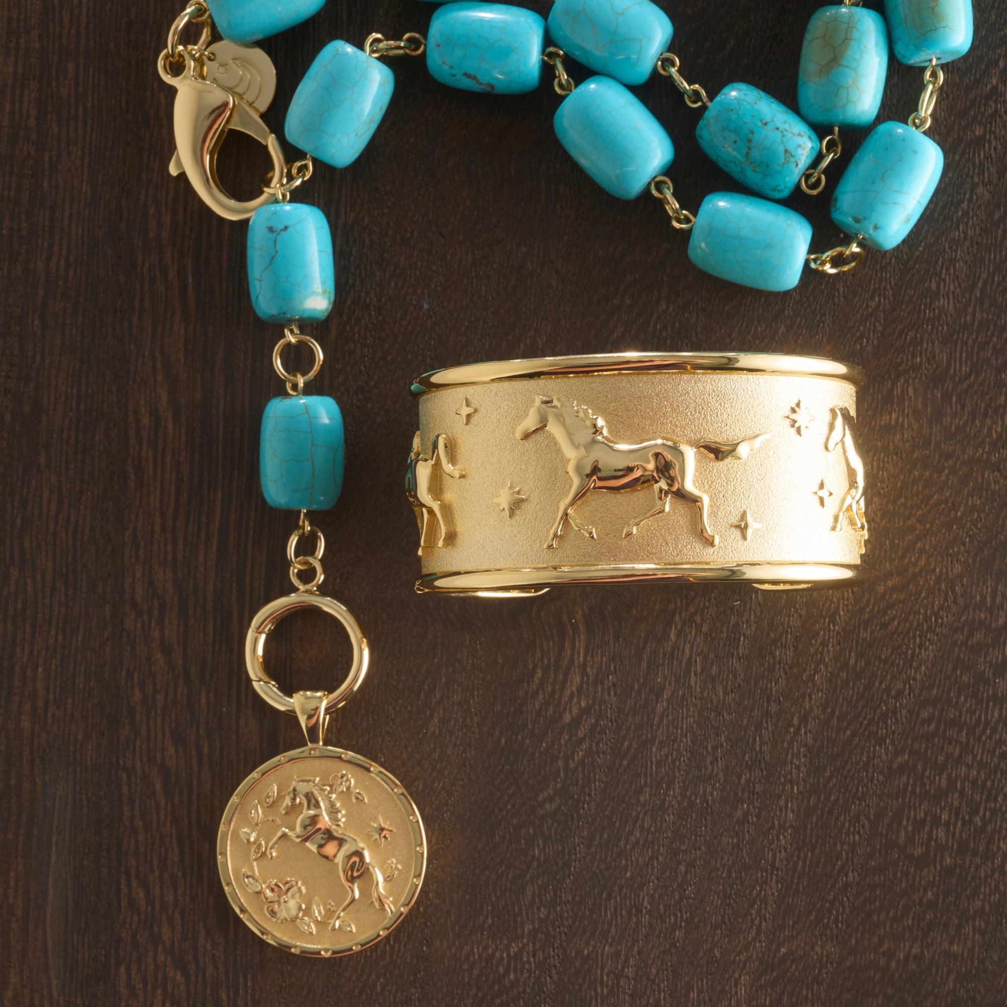 Stylized shot of chunky turquoise lariat with the courage year of the horse coin and the courage run with horses cuff