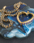 Stylized shot of the love you to the moon and back heart and made from love tennis necklace on a slice of blue agate