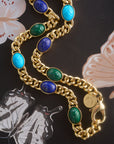 Stylized shot of the protect scarab curb chain with a painting of butterflies