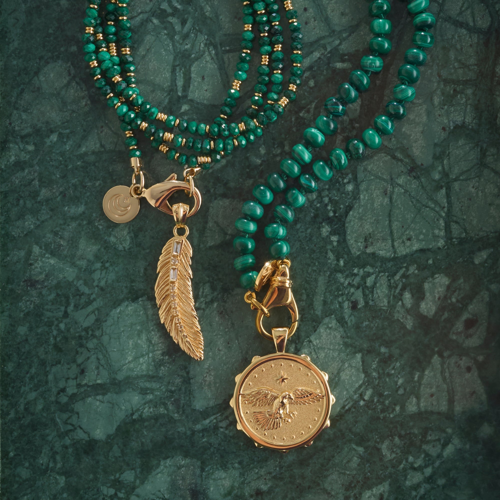 Stylized shot of the protect eagle coin, lucky feather pendant, malachite and gold double wrap necklace, and malachite beaded necklace.