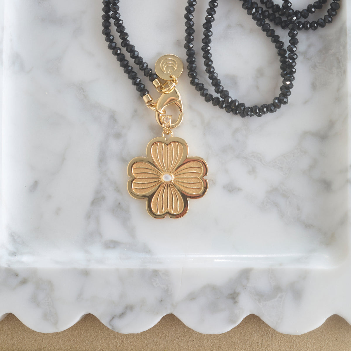 Stylized shot of the joy dogwood flower on the black agate double wrap chain