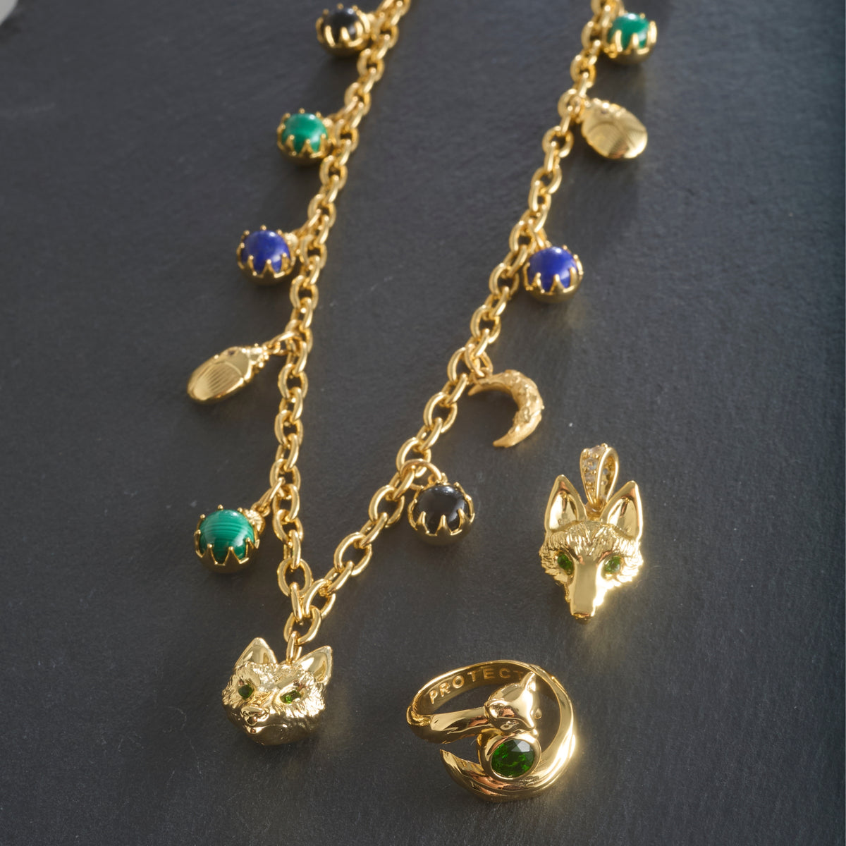 Stylized shot of the protect double wrap charm necklace, protect fox head pendant, and the protect fox ring