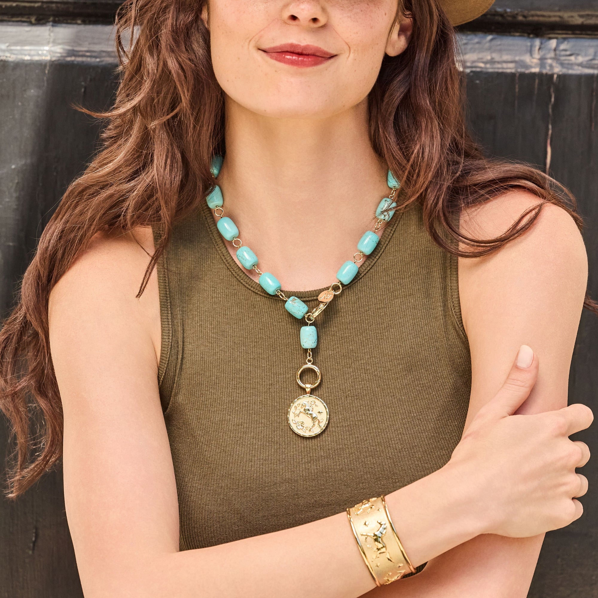 Model wearing the chunky turquoise lariat with the courage year of the horse coin pendant, as well as the courage run with the horses cuff bracelet
