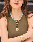 Model wearing the chunky turquoise lariat with the courage year of the horse coin pendant, as well as the courage run with the horses cuff bracelet