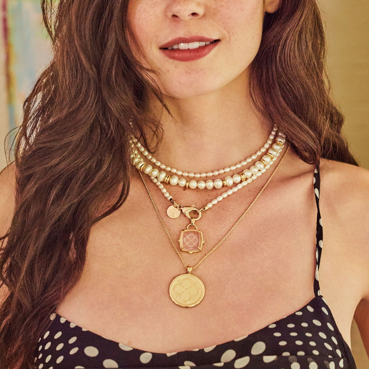 Model wearing the love carved glass pendant with various pearl necklaces and the love original coin