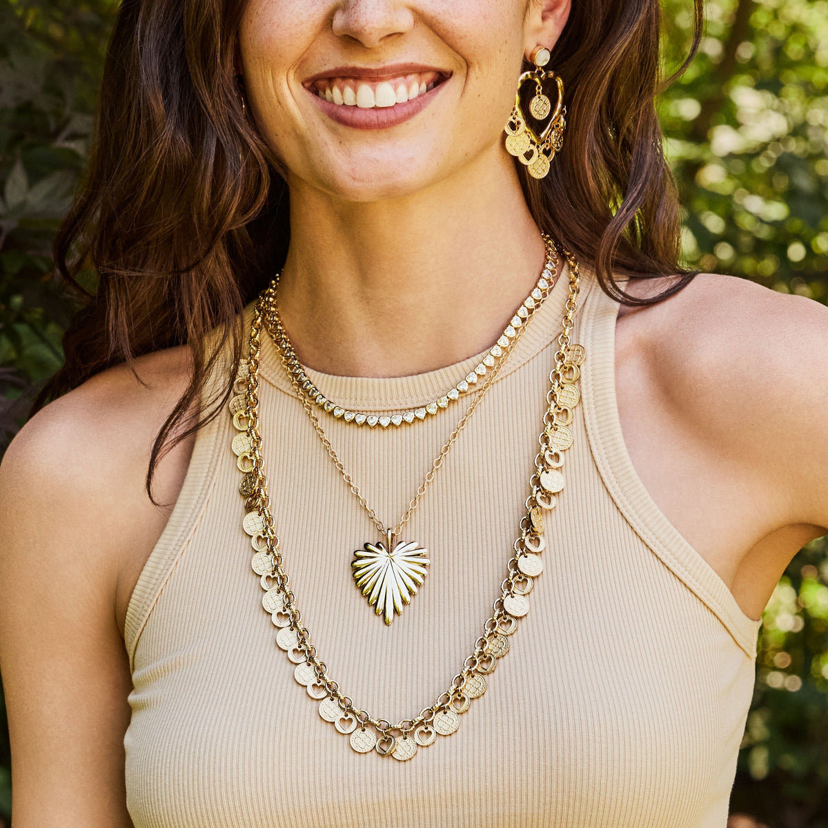 Model wearing the love amore coin necklace, full heart pendant, made from love tennis necklace, and the love amore coin earrings