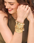 Model wearing a stack of chunky gold cuffs and chain bracelets