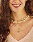 Model wearing the wheels of fortune chain, pearl double wrap, and the dogwood letter A pendant