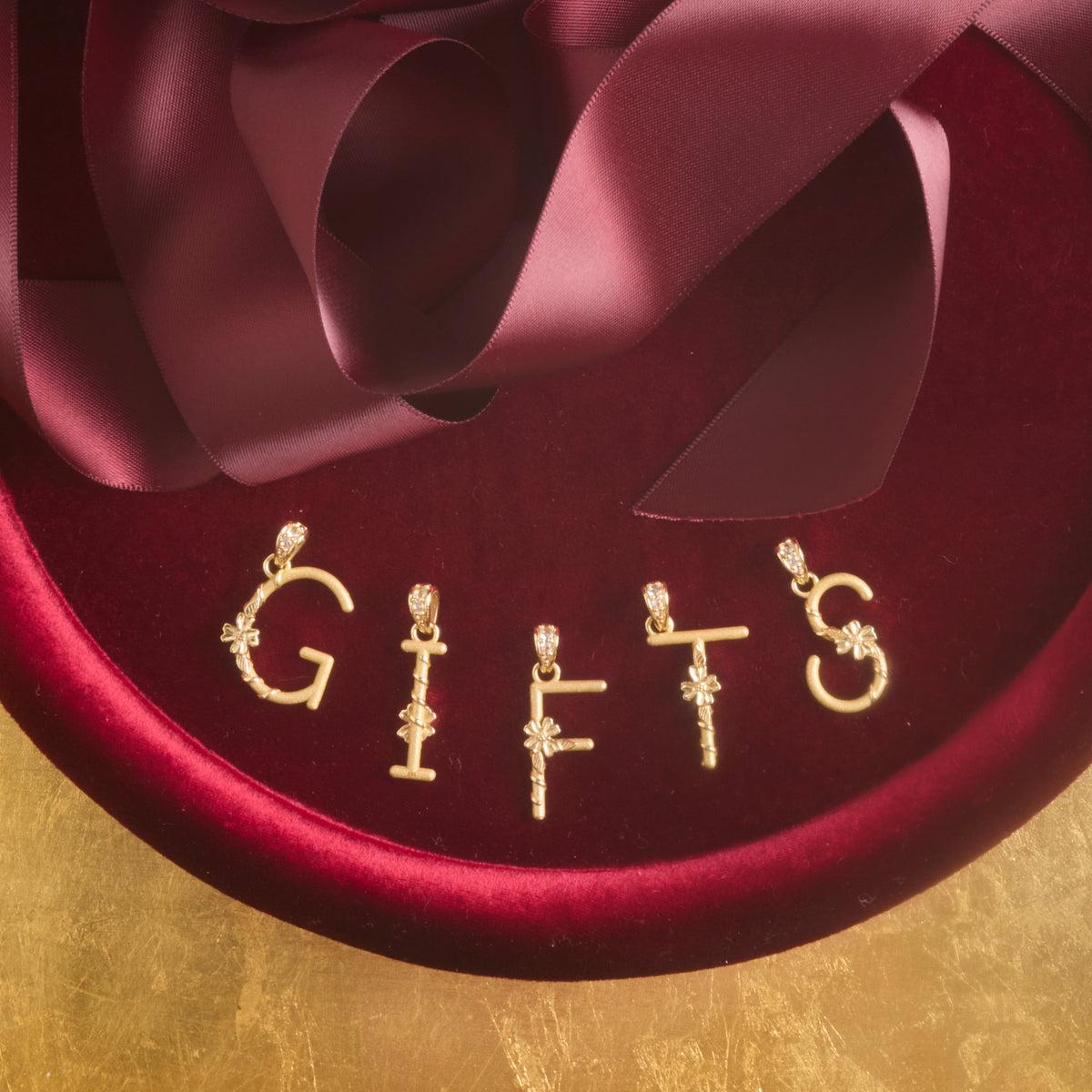 Stylized shot of the dogwood letter pendants spelling the word GIFTS