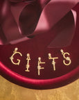 Stylized shot of the dogwood letter pendants spelling the word GIFTS