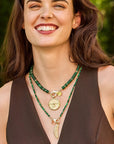 Model wearing the protect eagle coin pendant on the malachite gumdrop necklace and the lucky feather pendant on the malachite and gold double wrap