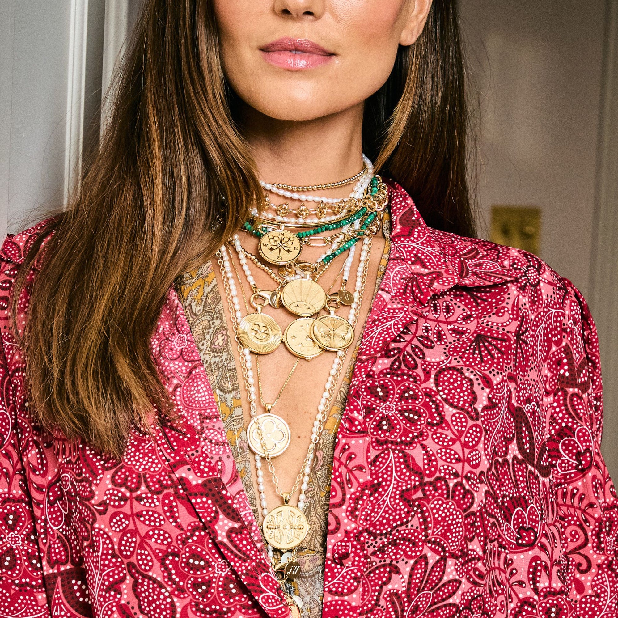 Model wearing assorted gold coin pendants and chains