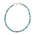 Beaded necklace with turquoise, lapis, and tigers eye beads and flat gold beads interspersed. Features oversized gold lobster clasp.