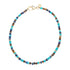 Beaded necklace with turquoise, lapis, and tigers eye beads and flat gold beads interspersed. Features oversized gold lobster clasp.
