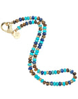 Beaded necklace with turquoise, lapis, and tigers eye beads and flat gold beads interspersed. Features oversized gold lobster clasp.