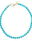 Beaded necklace features turquoise beads with smaller alternating coral and gold beads between them. Necklace has oversized gold lobster clasp