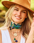 Model wearing assorted pendants and chains and malachite heart studs
