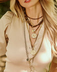 Model wearing assorted coin pendants and tigers eye beaded necklaces